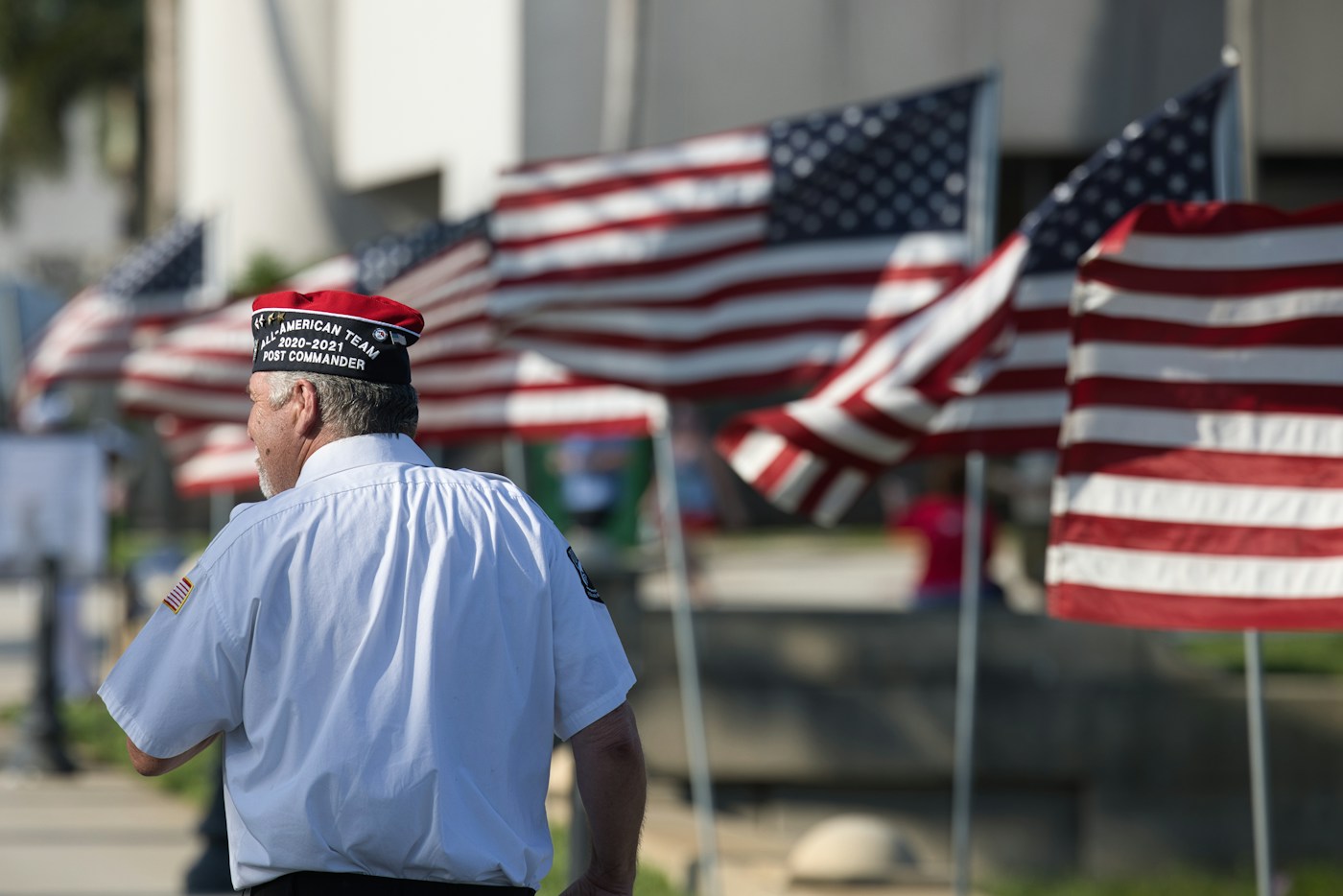 Stock photograph of a man wearing a veterans organization cap near American flags